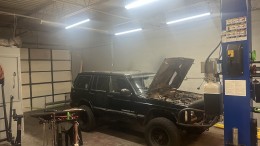 Black Jeep Cherokee with its hood open, undergoing maintenance or repair